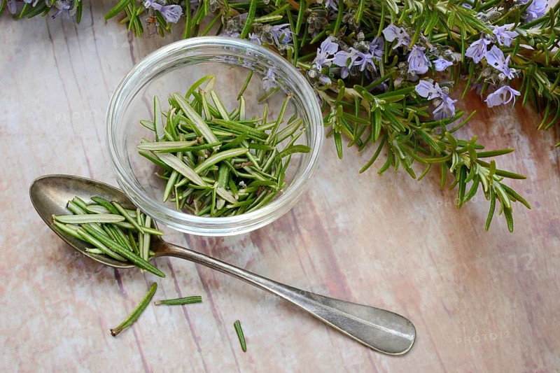 Rosemary, plucked rosemary leaves in a glass bowl and flowering sprig