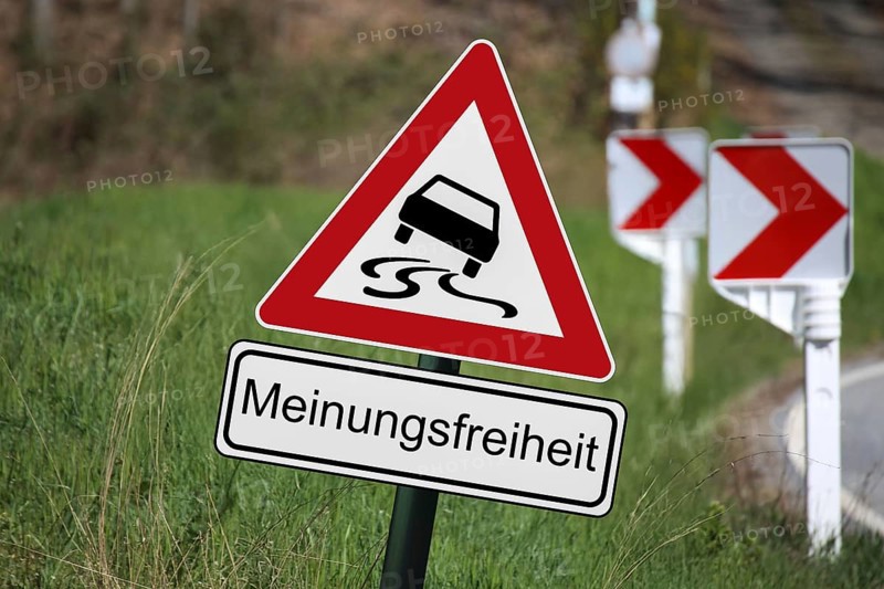 (Photomontage) : Traffic sign with danger of skidding, underneath a sign with the text MEINUNGSFREIHEIT