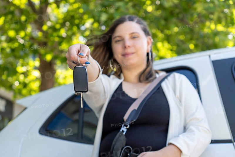 Proud businesswoman holding car keys in front of her new electric car, smiling with satisfaction and excitement over her recent purchase and the journey ahead