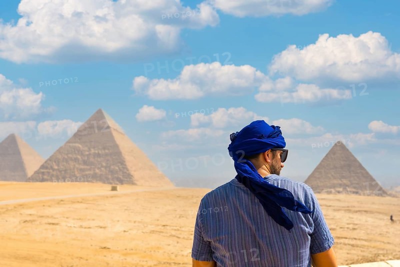 A young tourist wearing blue turban and sunglasses enjoying the Pyramids of Giza, the oldest Funerary monument in the world. In the city of Cairo, Egypt
