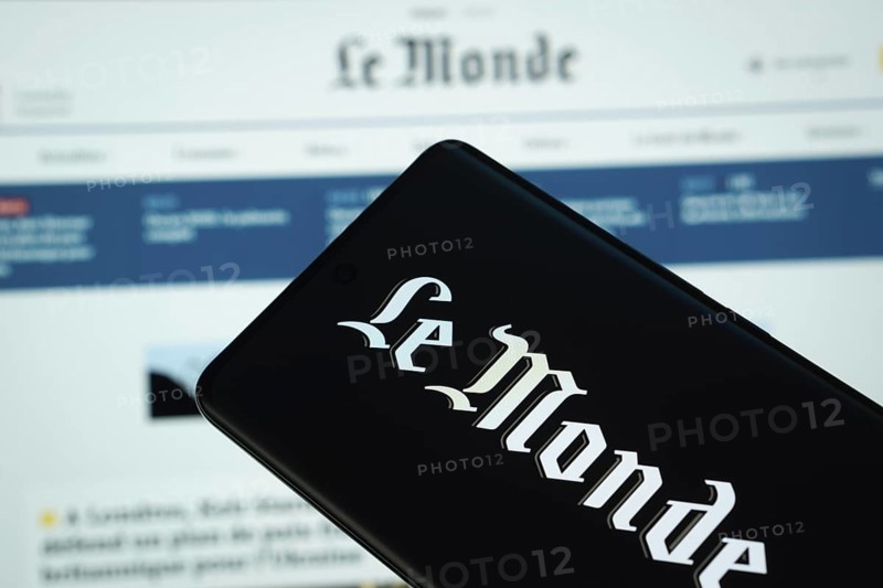 The logo of the newspaper le monde is displayed on a smartphone screen, and the website le monde is visible on a computer screen in the background