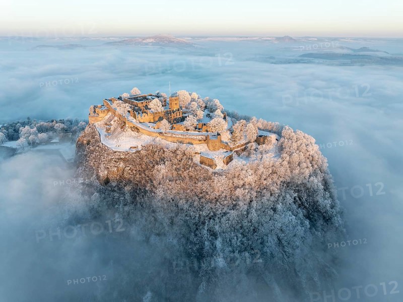 Aerial view of the Hegau volcano Hohentwiel with Germany's largest fortress ruins on a cold, foggy winter morning, at sunrise, on the horizon seen from the left the Hegau mountains Hohenstoffeln, Hohenhewen and Mägdeberg, Singen am Hohentwiel, district of Constance, Baden-Württemberg, Germany