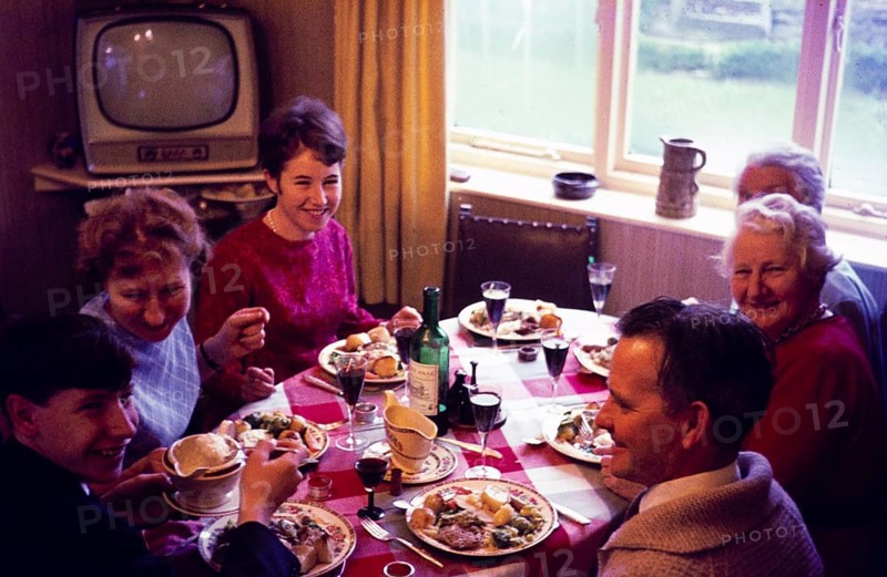 Traditional family Christmas meal all sitting around table eating and drinking, c 1960, England, UK