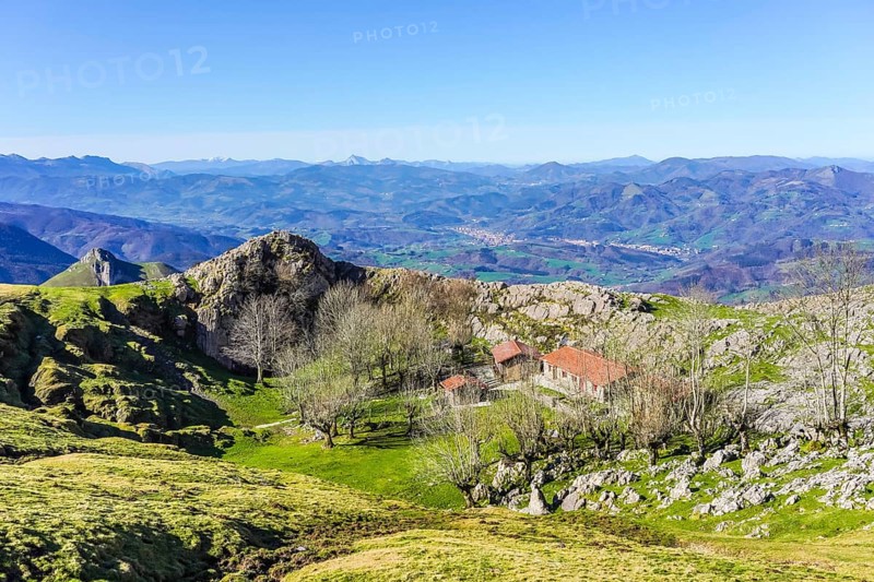 Scenic view of a mountain landscape featuring a traditional basque building nestled among trees, showcasing the beauty of the basque country
