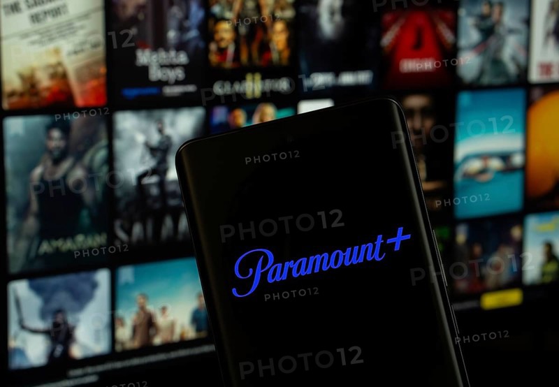 Dhaka, Bangladesh - 17 March 2025: The logo of the paramount+ is displayed on a smartphone screen, and the website paramount+ is visible on a computer screen in the background