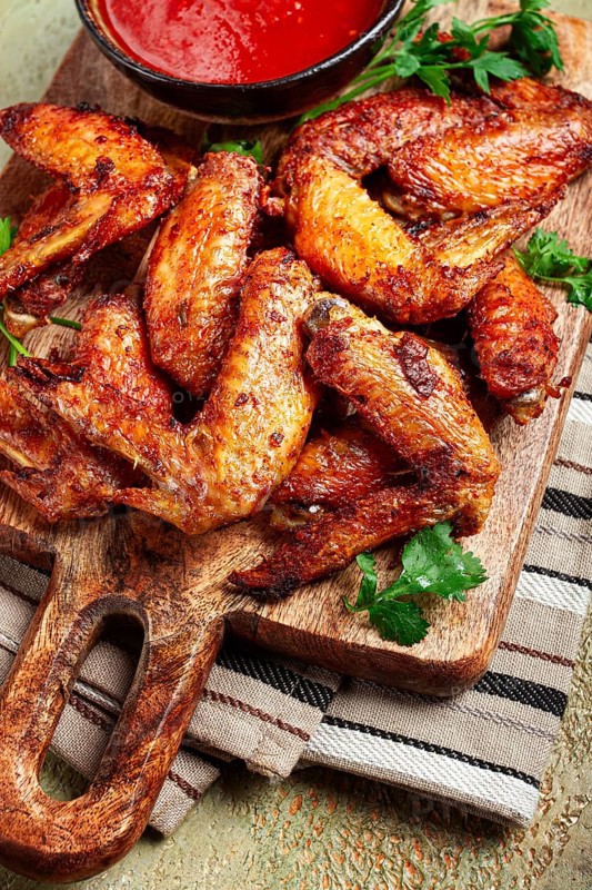 Fried in the oven, chicken wings, with spices, tomato sauce, on a cutting board, gray background, no people, homemade