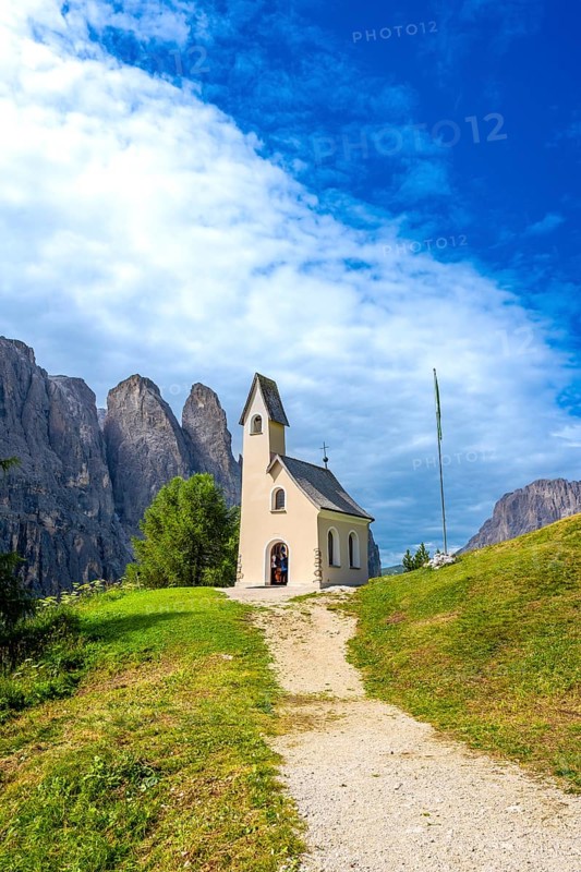 Small church at passo gardena with the dolomites in the background during a sunny summer day