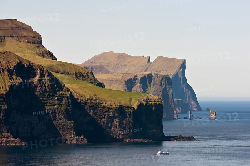 Fishing boat in front of Eysturoy, the basalt columns Risin and Kellingin at the back, Kalsoy, Faroe Islands, Denmark