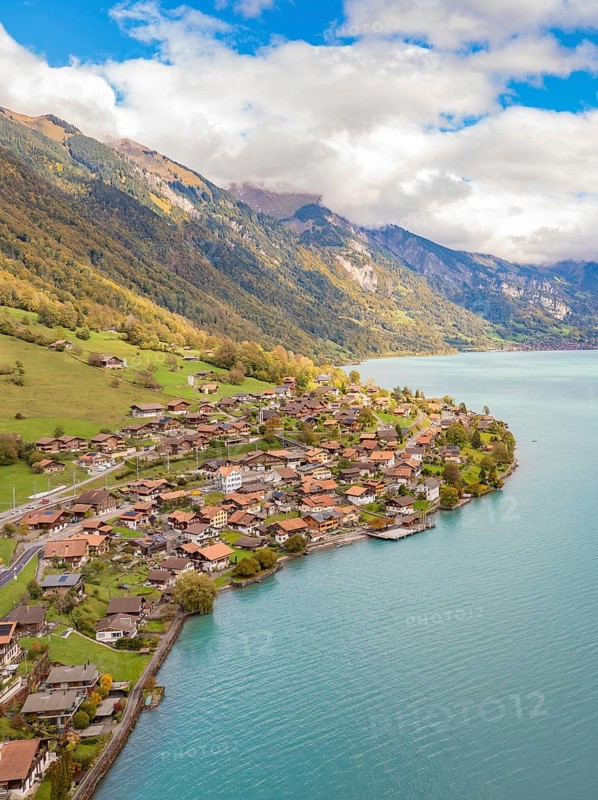 Alpine village on a lake with meadows and autumn colours, framed by mountains, Lake Brienz. Switzerland
