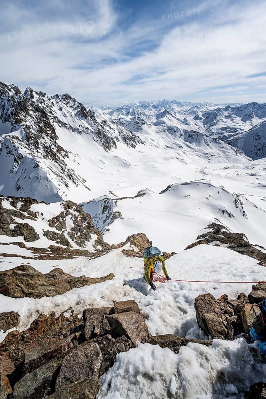 Mountaineer belaying on a steep snow slope, belaying on a rope, ascent to the summit of Piz Grialetsch in winter, view of mountain panorama with Piz Vadret with snow, Grisons Haute Route, Albula Alps, Rhaetian Alps, Grisons, Switzerland