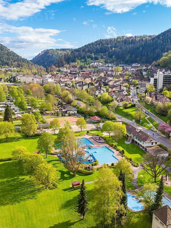 Overview of park with outdoor pool and town in the background in mountainous surroundings, Bad Liebenzell, district of Calw, Black Forest, Germany
