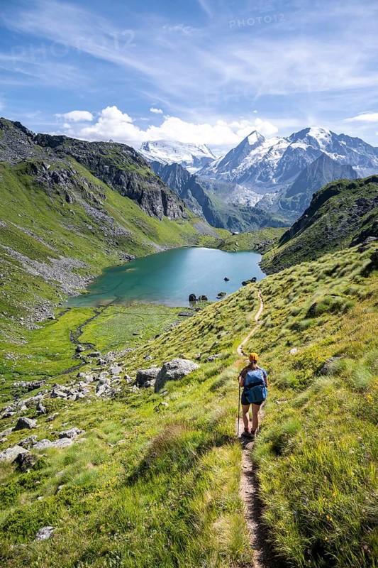 Hiker, mountain lake Lac de Louvie with glaciated summit of the Grand Combin, Val de Bagnes, Valais, Switzerland
