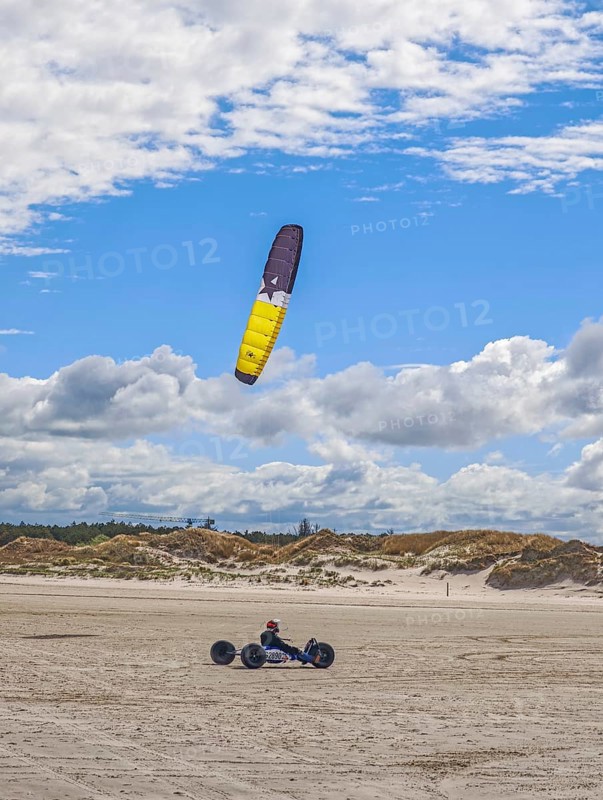 Recreational sport Beach kiting on the edge of the national park and UNESCO World Heritage Site, designated kite area, kite buggy steered with both feet, driver's seat with kiter between rear axle and front wheel, high speed, westerly winds, dunes on the beach, sunshine and blue sky, Sankt Peter-Ording, Schleswig-Holstein, Germany