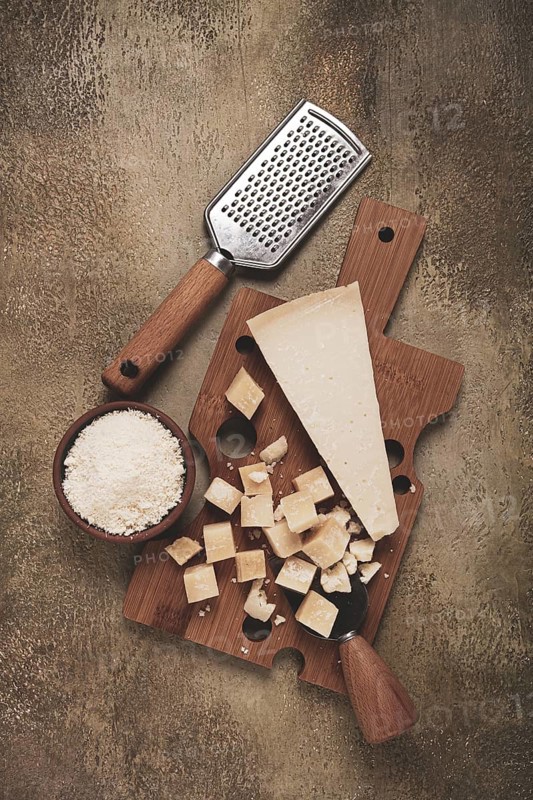 Freshly sliced and grated cheese, parmesan cheese, Gran gusto. Grana padano. on a wooden chopping board, rustic style, no people