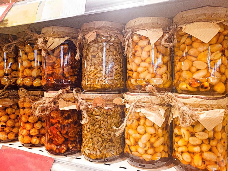 Jars of honey filled, with various nuts and seeds, are displayed on the store shelf, no people, mobile photo