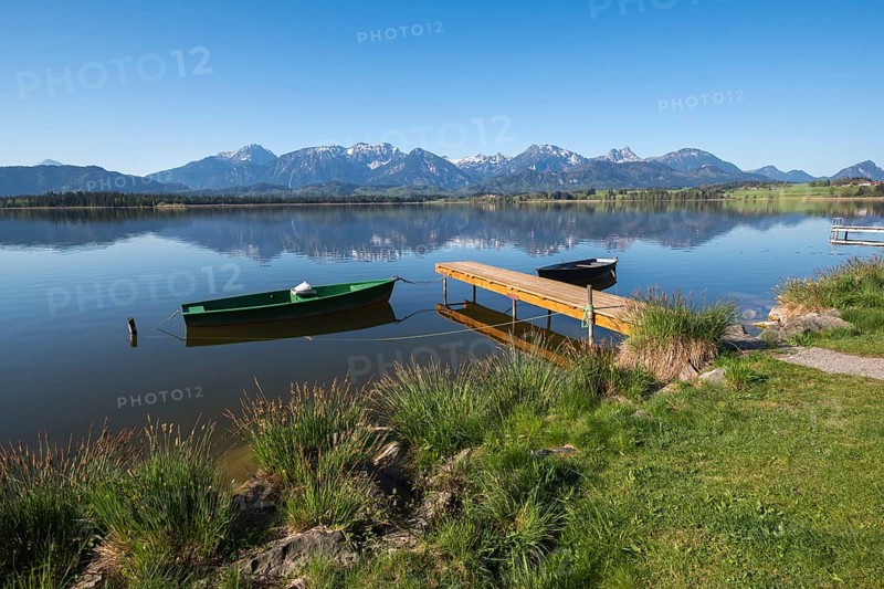 Landscape with green and black boat at a lake, surrounded by mountain peaks, Hopfen am See, near Füssen, district Ostallgäu, Swabia, Bavaria, Germany