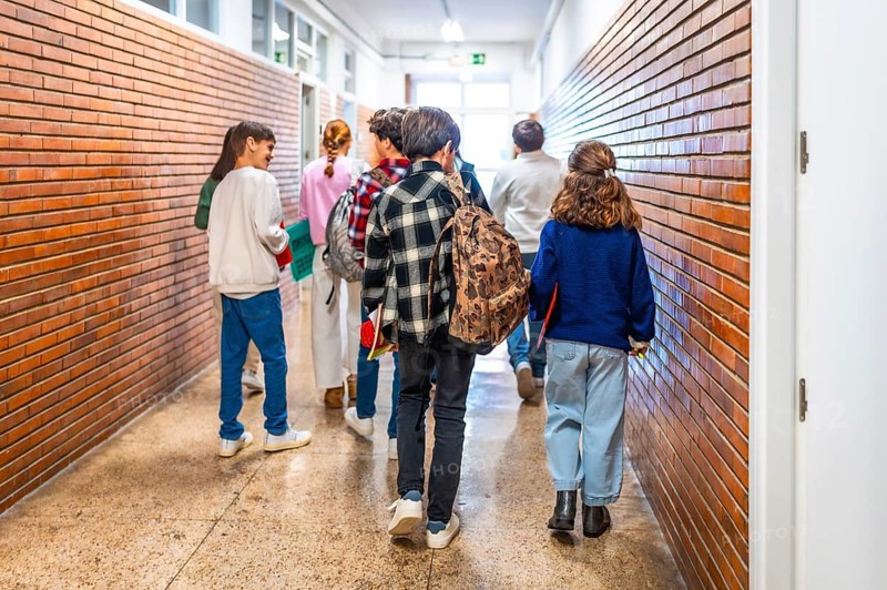 Group of elementary school students walking down the school hallway, chatting and laughing together as they transition between classes