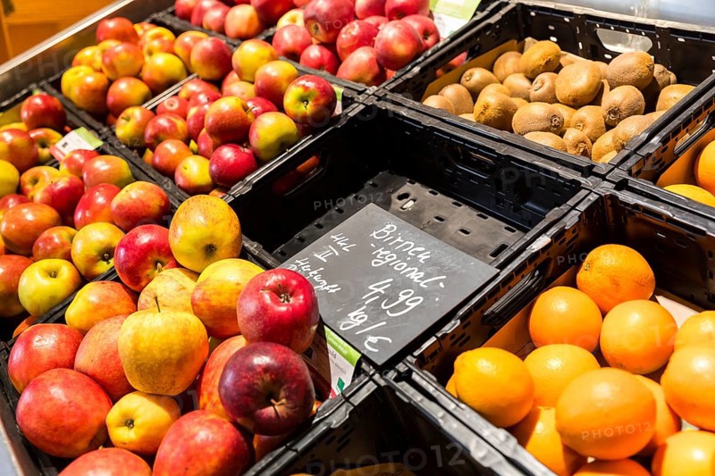 Fruit counter in a supermarket or organic food shop, here with different types of apples, kiwis, oranges and an empty compartment for pears