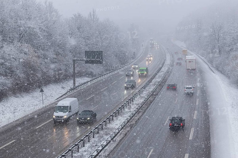 Snow-covered motorway with moving vehicles and snow-covered trees on the roadside, Winnenden, Baden-Württemberg, Germany
