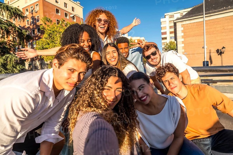 Frontal view of a multi-ethic cheerful friends taking selfie together in the city