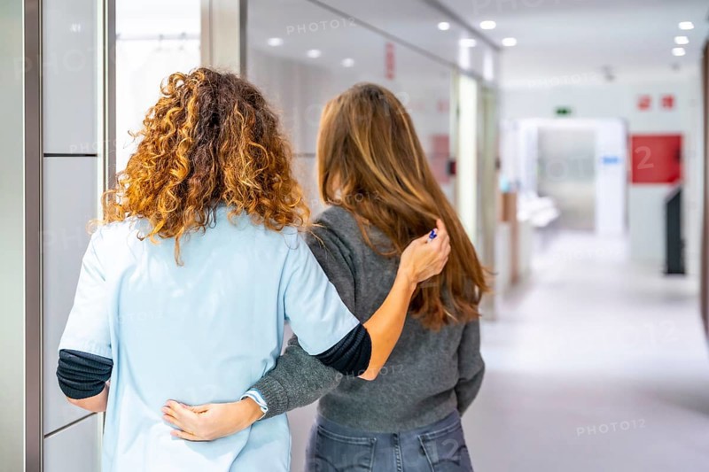 Rear view of a nurse accompanies a patient to the consultation in the hospital