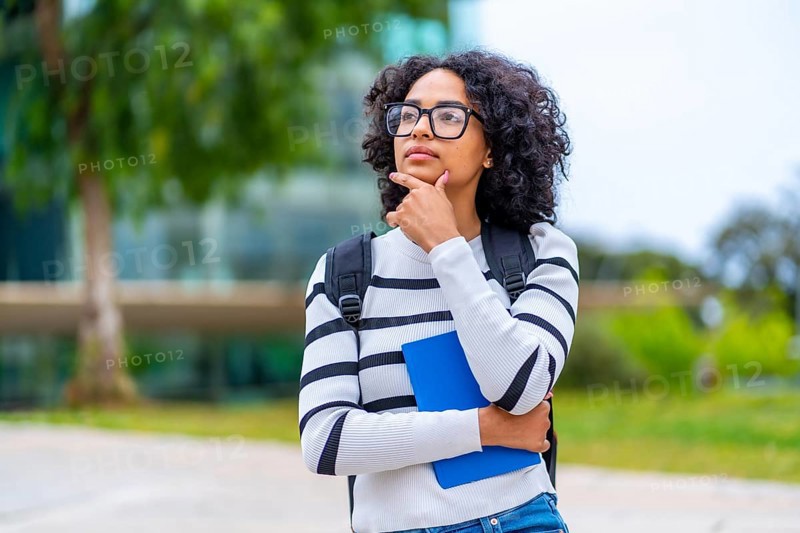 Portrait of a latin young female university student stranding hand on chin and thoughtful expression