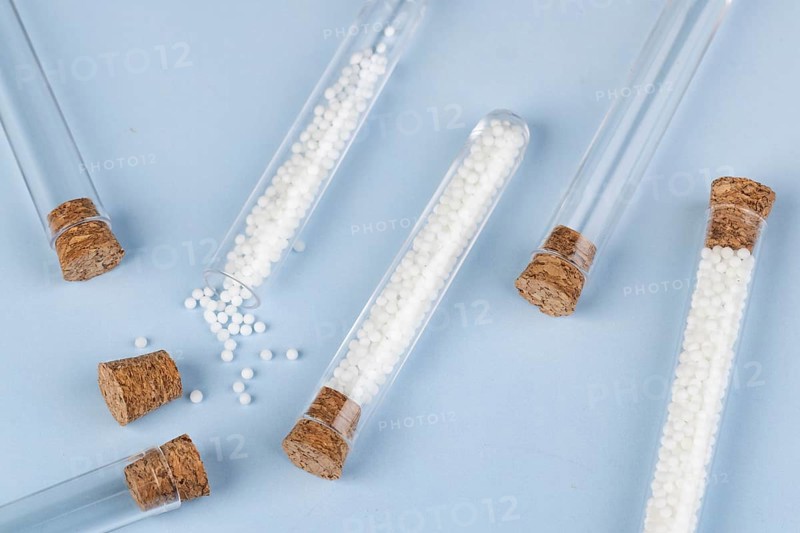 Test tubes with white globules and corks spread out on a blue background