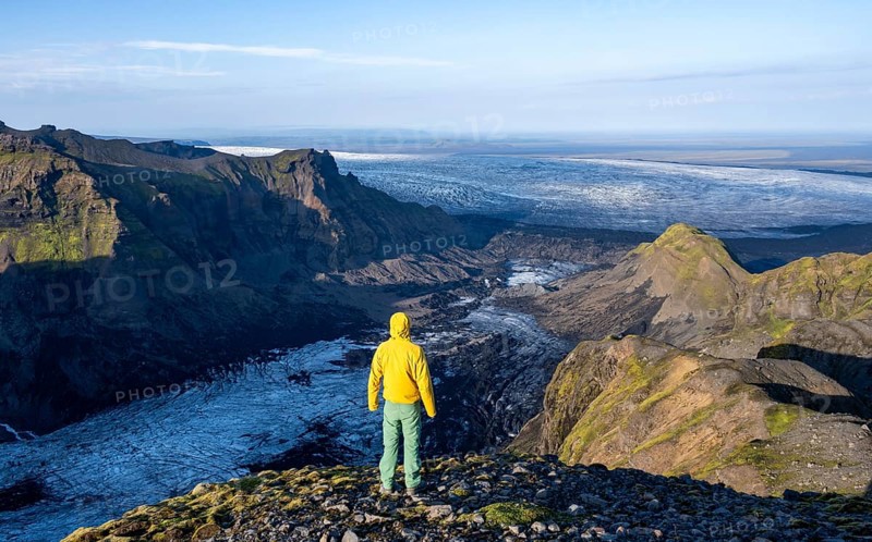 Young man, tourist in front of impressive landscape with glacier in the evening light, glacier tongues Huldujökull and Kötlujökull, Myrdalsjökull glacier, Pakgil, Iceland