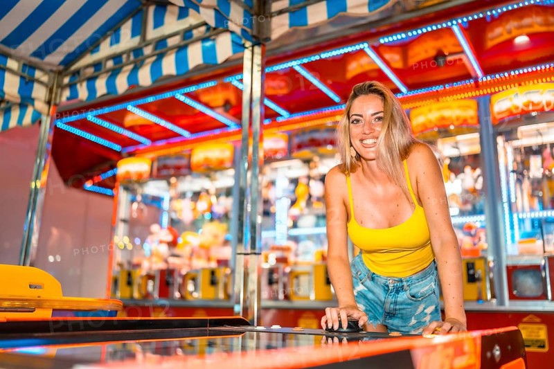 Blonde caucasian smiling woman playing arcade games at night in an amusement park