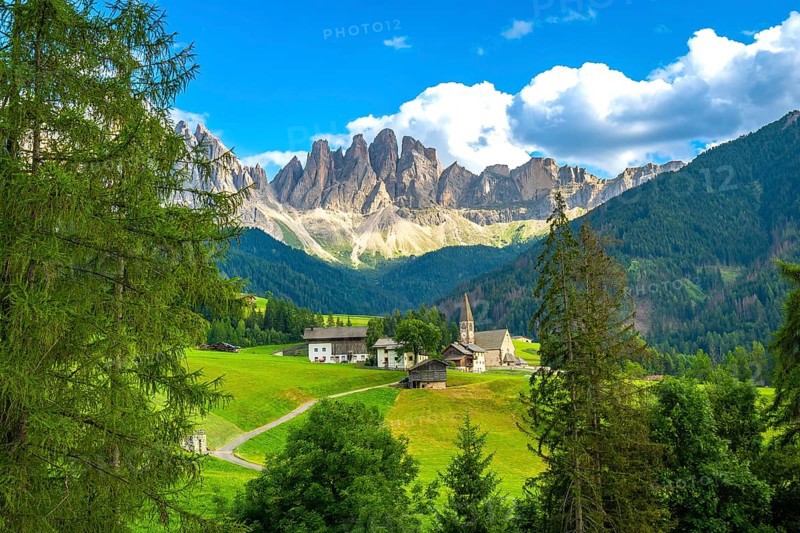 Scenic landscape showing st. Magdalena church in val di funes with the odle mountain range in the background during a sunny summer day