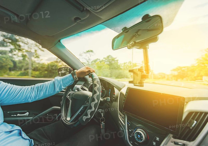 Interior view of a man driving a car. Driver hands on the steering wheel