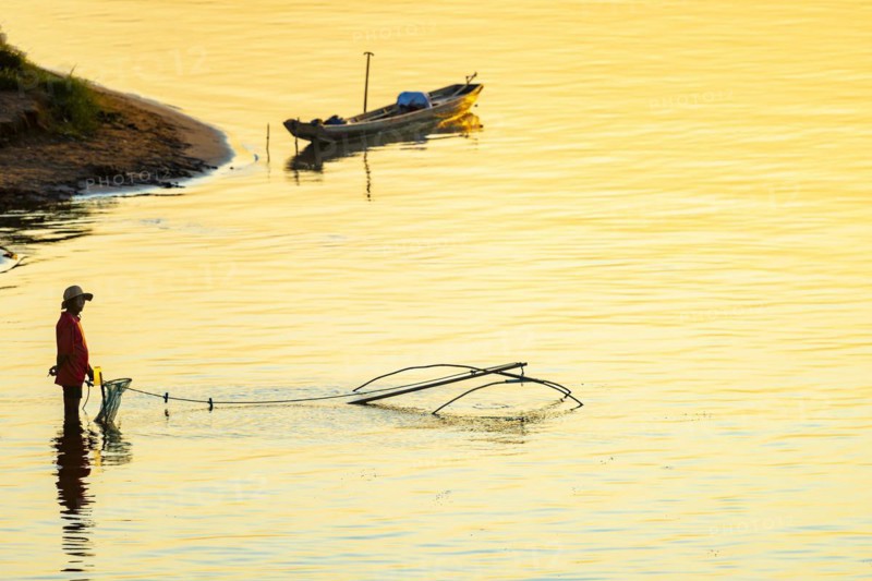 Fisherman with a sinking net at sunset on the Mekong, Luang Prabang, Laos