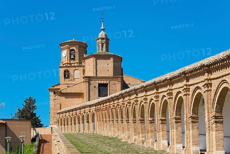 Historisches Backsteingebäude mit Bögen und einem Uhrturm unter blauem Himmel, Basílica de Nuestra Señora del Romero, Basilika Unserer Lieben Frau von Romero, Cascante, Navarra, Spanien