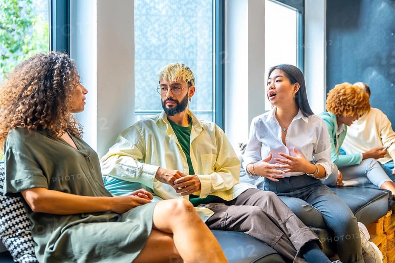 Side view of three coworkers chilling and talking in a comfortable sofa