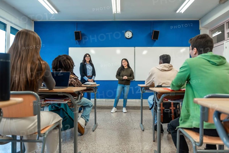 Confident young woman giving a presentation to her classmates and teacher in a modern university classroom