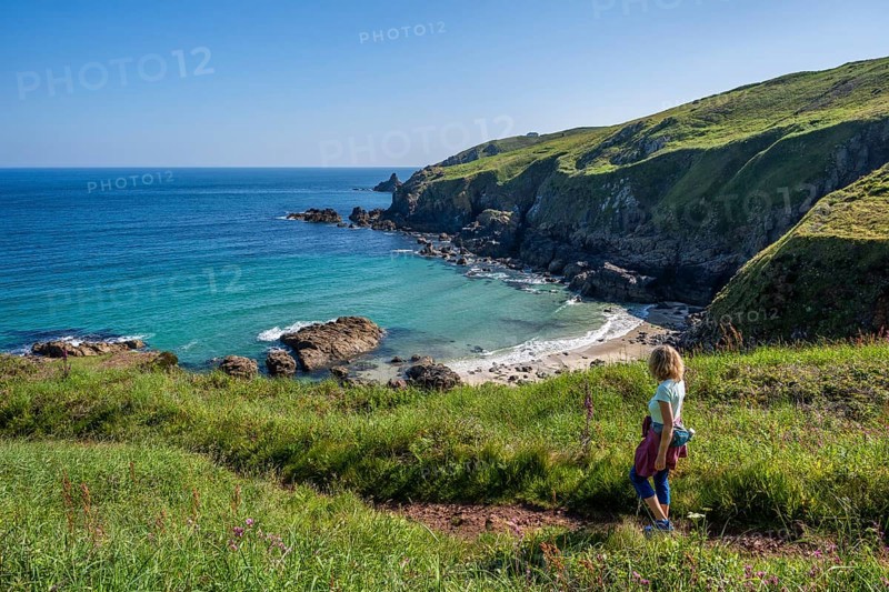 A hiker on a coastal path. View of Rose-an Hale Cove. Between Gurnard's Head and Carnelloe Headland. Cornwall, England, Great Britain