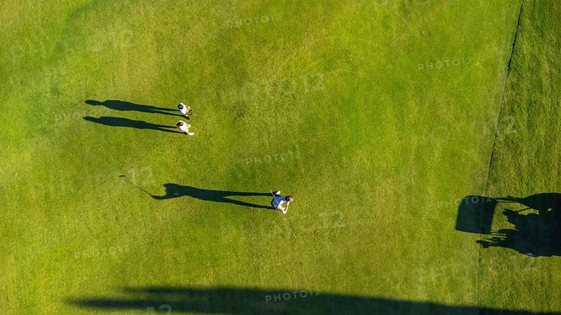Aerial top view of three people in a green luxury gold course