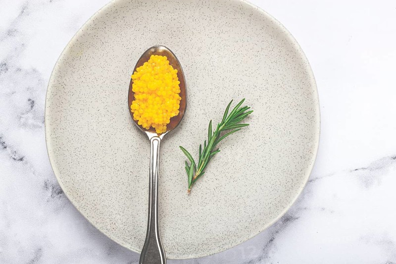 Yuzu caviar is pearly, on a spoon, top view, light background, no people.