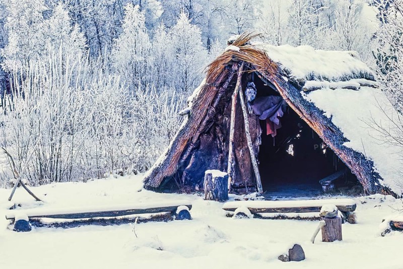 Reconstruction of a Stone Age settlement with a grass hut with snow and frost a cold winter day, Åsarp, Falköping, Sweden