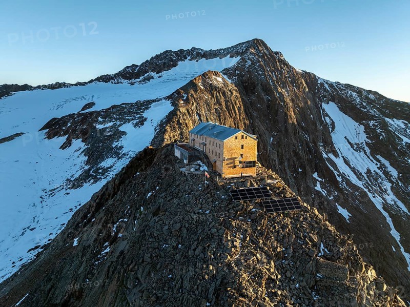 Atmospheric sunrise in a picturesque mountain landscape, alpenglow, aerial view, mountain hut Becherhaus at the summit Becher and glacier Übeltalferner, Stubai Alps, South Tyrol, Italy