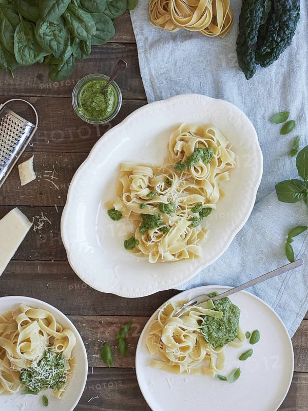 Green Tagliatelle pasta with spinach and kale pesto beside parmesan cheese. Traditional Italian meal