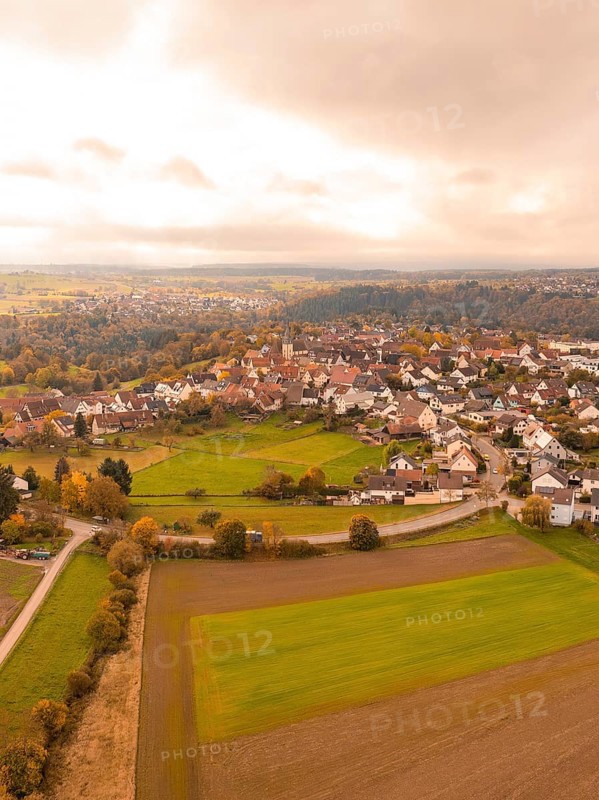 View of a village with autumnal fields and clouds, Tiefenbronn, Germany