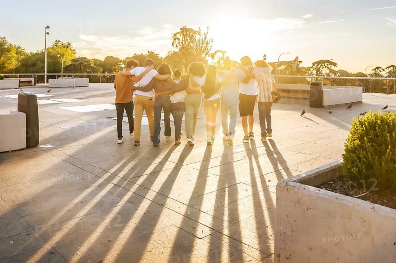 Rays of the sunset illuminating a group of friends having fun strolling together at city