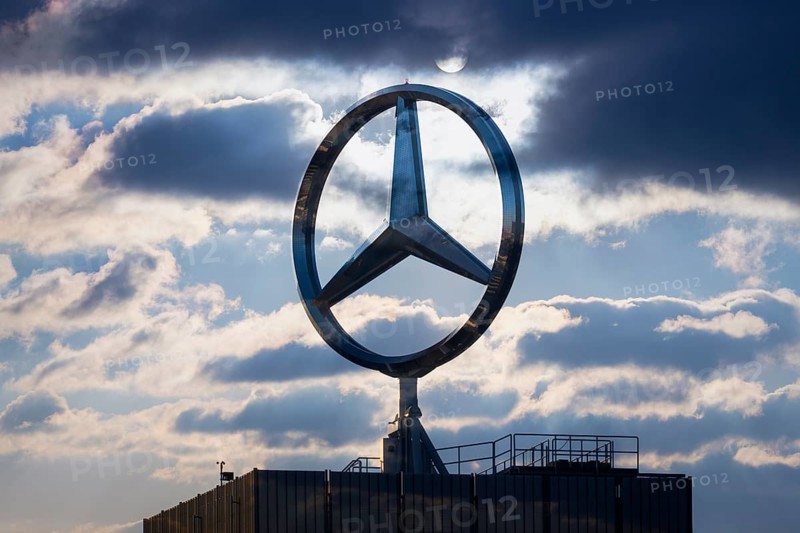 A Mercedes logo on a building in front of a cloudy sky with sunbeams, Baden-Württemberg, Germany