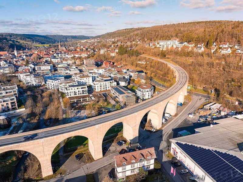 Aerial view of a town with viaduct, surrounded by hills and forests, under a blue sky, Nagold, Black Forest, Germany