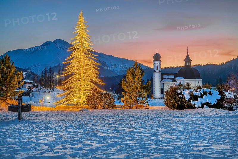 Seekirchl with artificially illuminated winter fir tree and Hocheder 2797m at dusk in winter, Seefeld, Seefeld Plateau, Tyrol, Austria