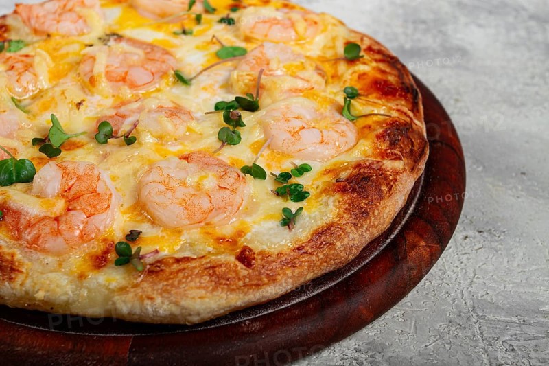 Four cheese pizza with shrimp and fresh microgreens, served on a wooden board, homemade, no people