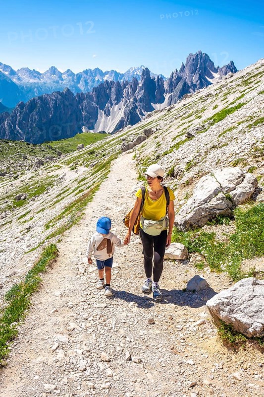 Tourists enjoying a summer hike on a mountain path in the italian alps, with breathtaking views of the tre cime di lavaredo