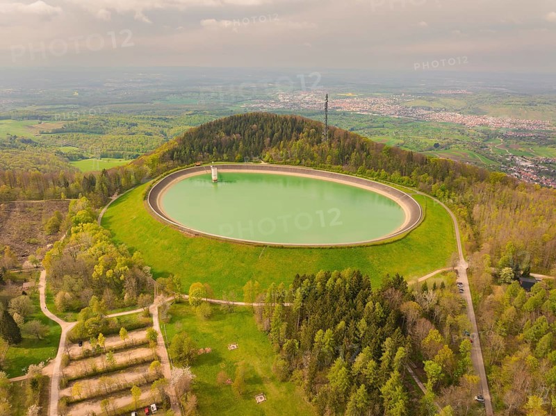 Upper reservoir hill with reservoir and forest, observation tower in the background under cloudy sky, Glems reservoir, Swabian Alb, Germany