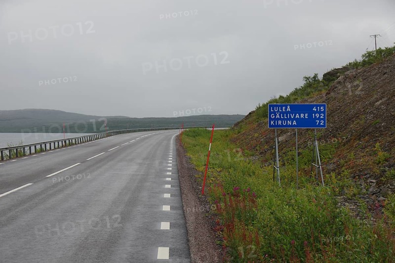 Lonely country road under cloudy sky with road sign pointing towards Luleå and Kiruna, autumn in Lapland, Torneträsk, Abisko, Sweden